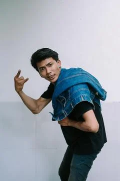 A man striking a pose with a jacket draped over his shoulder, exuding confi.. Stock-Fotos