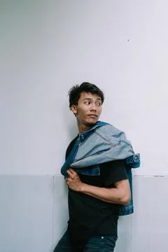 A man striking a pose with a jacket draped over his shoulder, exuding confi.. Foto stock