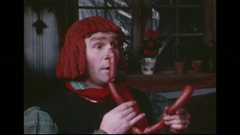 A man with a string of sausages attached to his nose fondles the sausages as a Stock Footage 74778484
