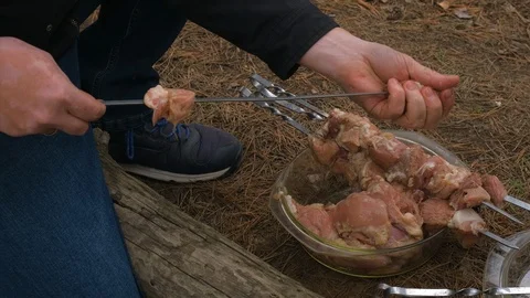 Man stringing kebab on a skewer. Cooking kebabs on the nature Stock Footage 126955259
