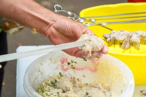 Man stringing marinated meat on skewer for barbecue Stock-Fotos