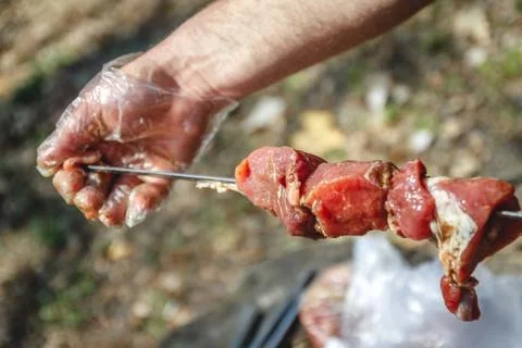 Man stringing meat on a skewer. Close-up. Stock Photos