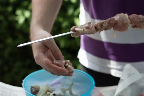 Man stringing meat on a skewer prepares a shish kebab Stock Photos