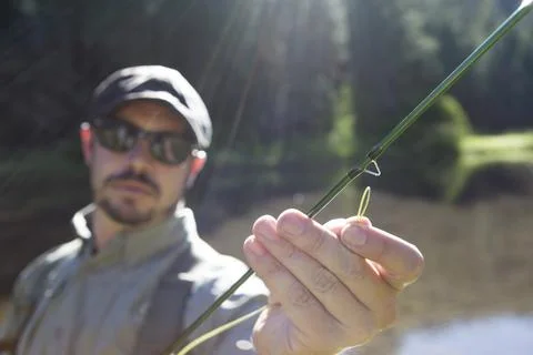 Man strings a fly rod near mountain river Stock Photos