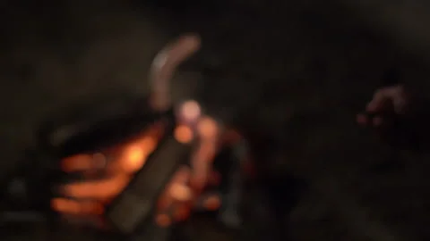 A man strings a sausage on a stick and roasts it over a fire at night. Camping Stock Footage 252145406