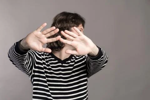 Man in striped sweater turns aside, stretching his hands forward. Pushing Stock Photos