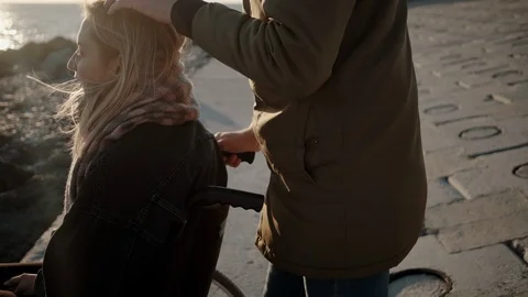 Man is stroking head of his beloved woman in wheelchair on sea coast Stock Footage 110540521