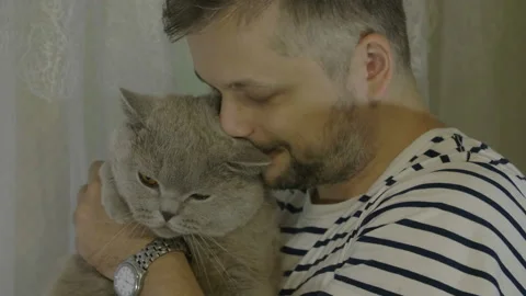 Man stroking his cat and talk with it. Close-up of cat's happy face. 库存影片 143978282