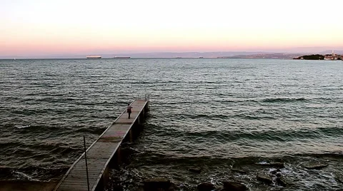 Man strolling along the pier and the waves lapping on the pier in the Adriatic. Video stock 68964531
