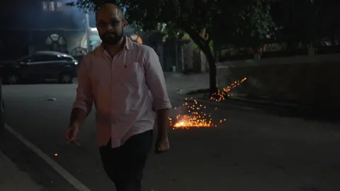 Man Strolling Past a Lit Firecracker on a Quiet Night Street in Slow Motion Stock-Footage 332470080