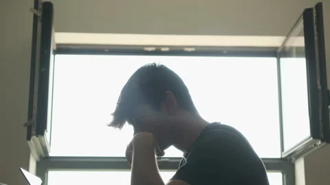 Man struggles to edit a video in a room. Silhouette &amp; contrast Stock Footage 243423818