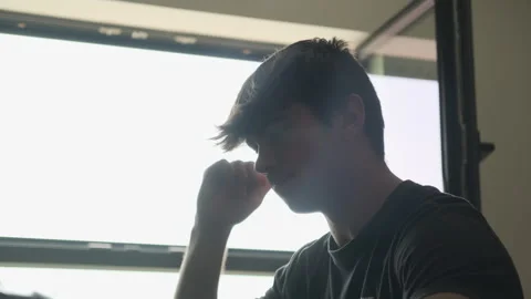 Man struggles to edit a video in a room. Silhouette &amp; contrast Stock Footage 243423846