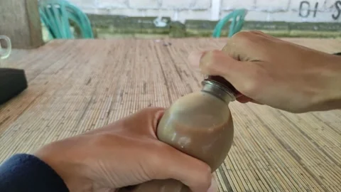 A man struggles to open a coffee bottle. Small bottle of coffee. Vidéo 198678989