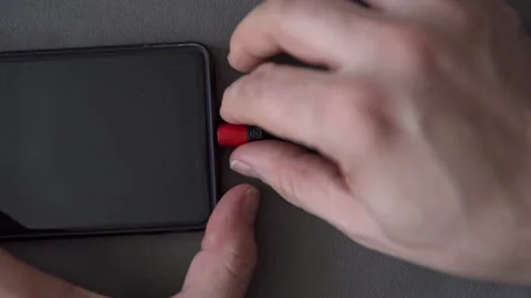 Man struggles to remove micro usb plug from cell phone socket Stock Footage 237628439