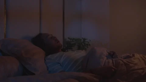 A man struggles to sleep, tossing and turning in bed at night Stock Footage 339514672