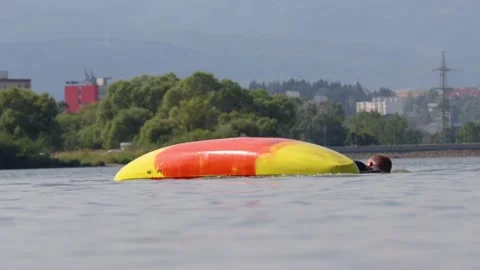 Man struggles in water in an upside down capsized kayak Stock Footage 169622692