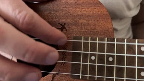 Man strumming ukulele strings close up at home, playing music, rhythm practice, Stock Footage 337104416