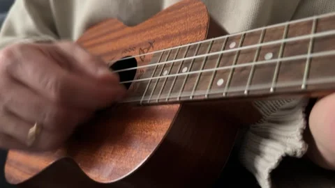 Man strumming ukulele strings close up at home, playing music, rhythm practice, Stock Footage 337105314