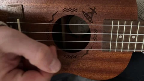 Man strumming ukulele strings close up at home, playing music, rhythm practice, Stock Footage 337105334
