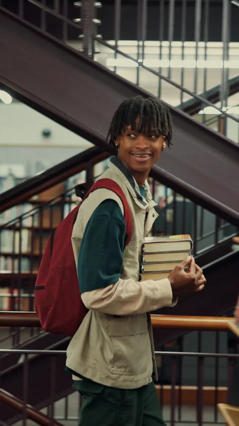 Man, student and walking with books in library for education, knowledge or Stock Footage 335804674