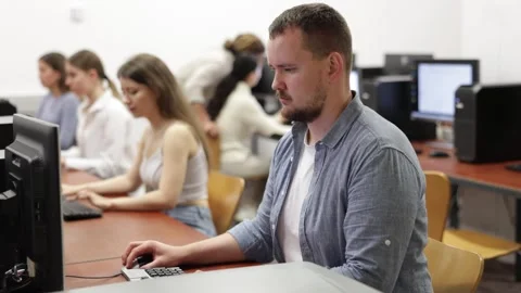 Man student of computer courses looks at monitor screen, types on keyboard and Stock Footage 315539235