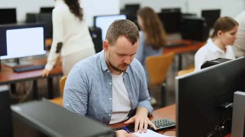 Man student of computer courses looks at monitor screen, types on keyboard and Stock Footage 317531356
