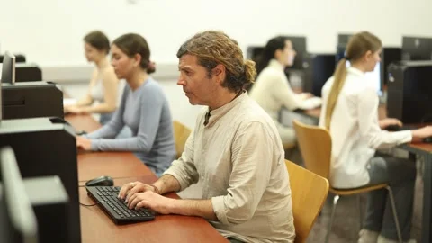 Man student of computer courses looks at monitor screen, types on keyboard and Stock Footage 319994323