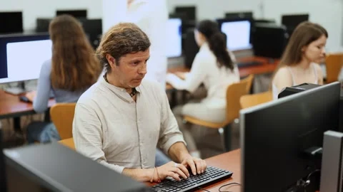 Man student of computer courses looks at monitor screen, types on keyboard and Stock Footage 322113072