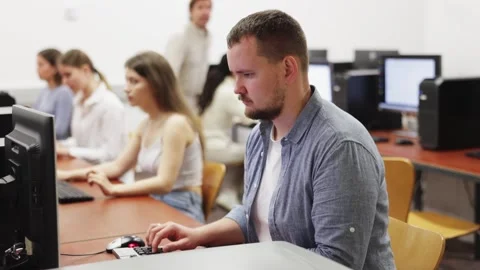 Man student of computer courses looks at monitor screen, types on keyboard and Stock Footage 325763566