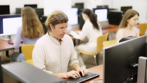 Man student of computer courses looks at monitor screen, types on keyboard and Stock Footage 341426385