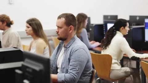 Man student of computer courses looks at monitor screen, types on keyboard and Stock Footage 343707375