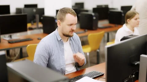 Man student of computer courses looks at monitor screen, types on keyboard and Stock Footage 344850997