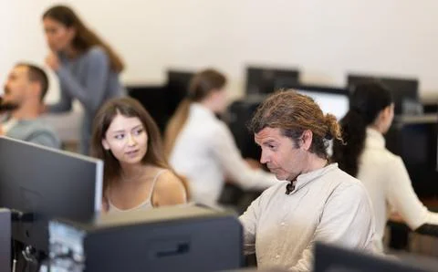 Man student of computer courses looks at monitor screen, types on keyboard and 写真素材