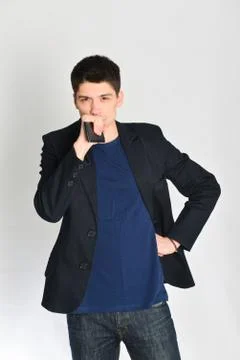 Man, student or freelancer in a jacket, emotionally posing with a phone Stock Photos