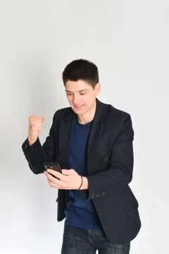 Man, student or freelancer in a jacket, emotionally posing with a phone Stock Photos