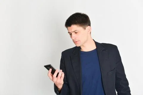 Man, student or freelancer in a jacket, emotionally posing with a phone Stock Photos