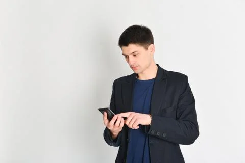 Man, student or freelancer in a jacket, emotionally posing with a phone Stock Photos