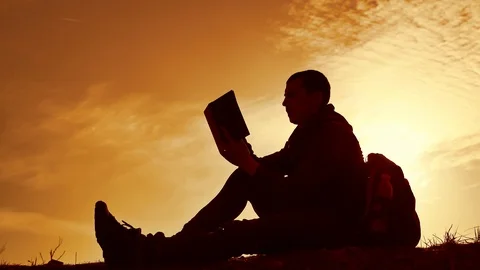 Man student reading in the park with backpack against sunset. Silhouette of man Stock Footage 88447507