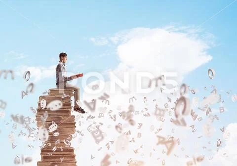 Man student on stack reading book and symbols flying around Stock Photos