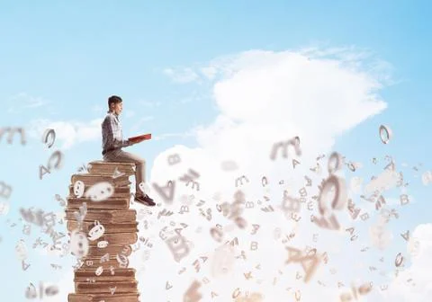 Man student on stack reading book and symbols flying around 스톡 사진