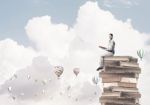 Man student on stack reading book and aerostats flying around Foto stock