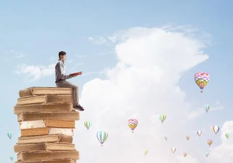 Man student on stack reading book and aerostats flying around Foto stock