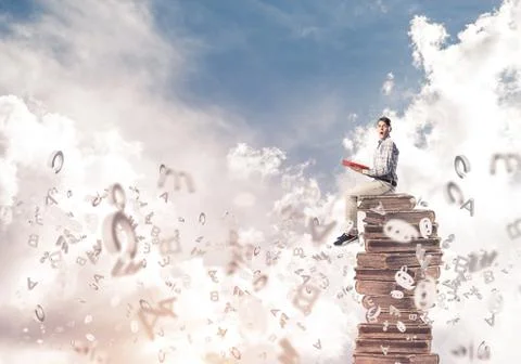 Man student on stack reading book and symbols flying around 库存照片