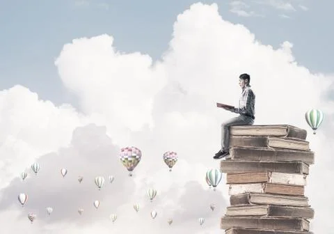 Man student on stack reading book and aerostats flying around Foto stock