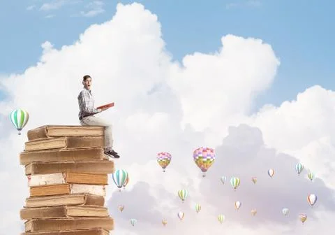 Man student on stack reading book and aerostats flying around Foto stock