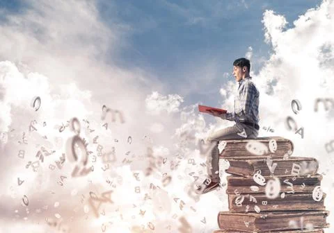 Man student on stack reading book and symbols flying around Foto stock