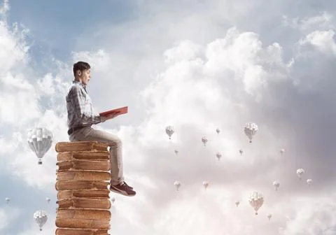 Man student on stack reading book and aerostats flying around 库存照片