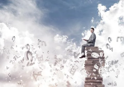 Man student on stack reading book and symbols flying around Foto stock