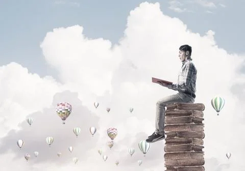 Man student on stack reading book and aerostats flying around Foto stock