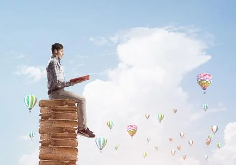Man student on stack reading book and aerostats flying around Foto stock